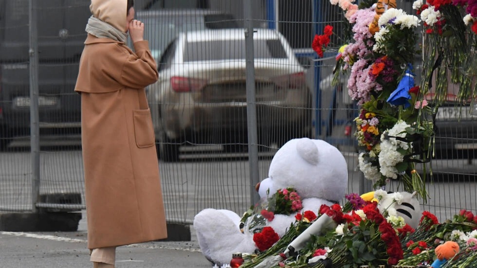 صورة مؤرخة في 23 آذار/مارس 2024 لامرأة أمام نصب تذكاري في موقه الهجوم على صالة كروكوس سيتي هول في ضاحية موسكو