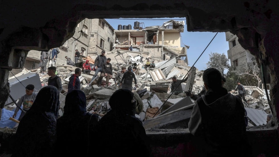 فلسطينيون يتفقدون انقاض أبنية دمّرها قصف ليلي في رفح في جنوب قطاع غزة في 27 آذار/مارس 2024