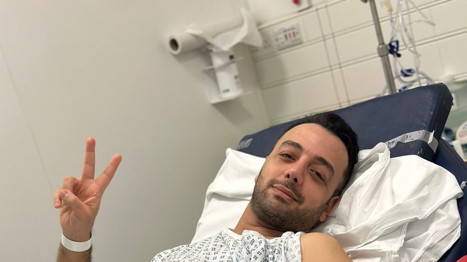 الصحفي الإيراني وشارة السلام من المستشفى اللندني بعد طعنه 