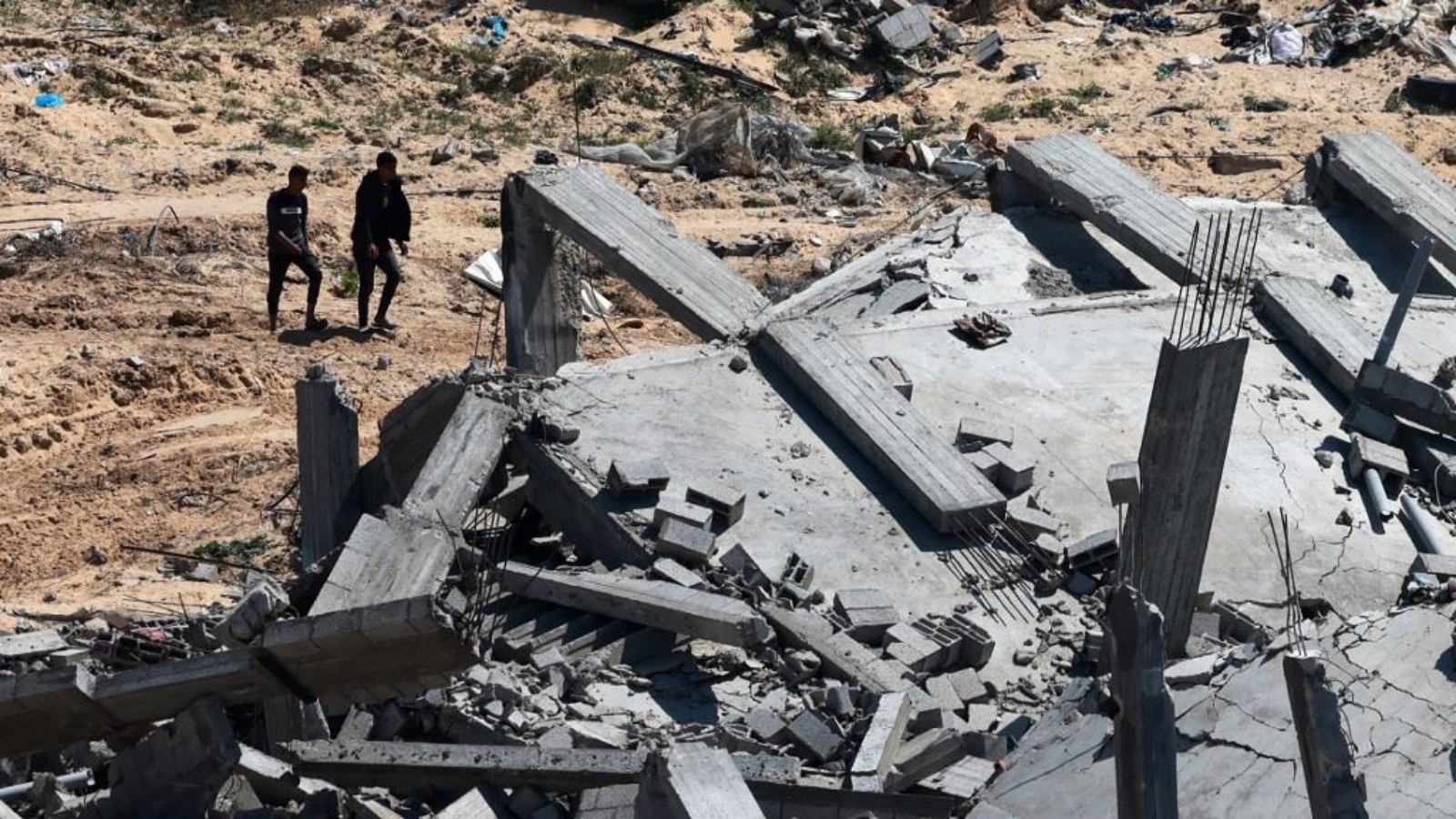 رجال يمرون قرب مبنى مدمر في خان يونس بعدما سحبت إسرائيل قواتها البرية من جنوب قطاع غزة (7 نيسان 2024، أ ف ب). رجال يمرون قرب مبنى مدمر في خان يونس بعدما سحبت إسرائيل قواتها البرية من جنوب قطاع غزة 7 نيسان (أبريل) 2024