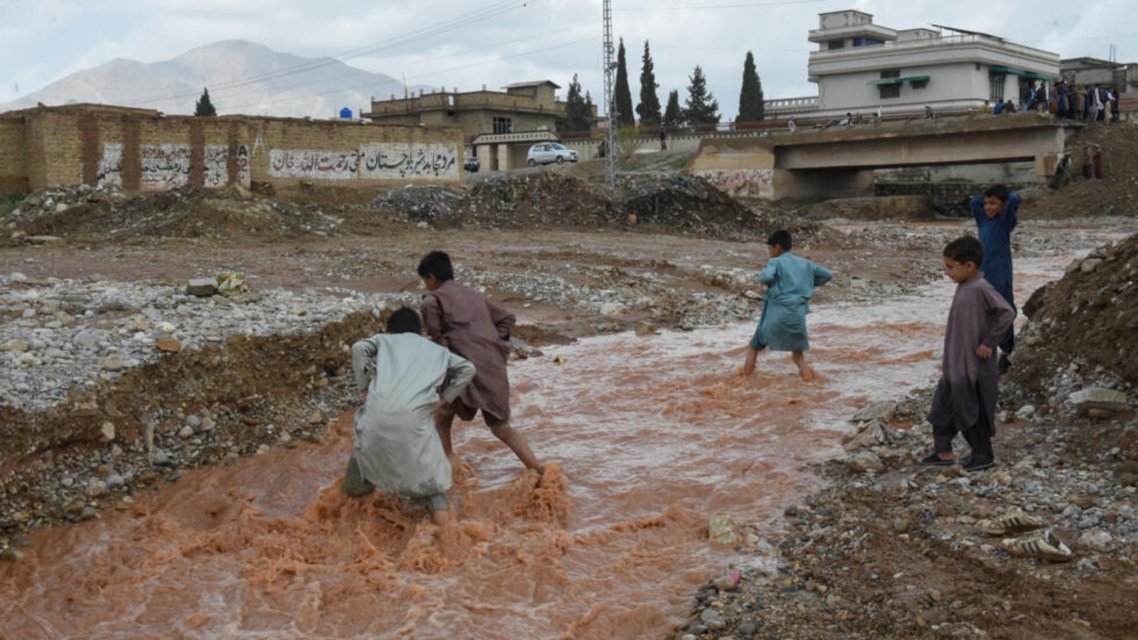 أطفال يجتازون مياه فيضانات بعد هطول أمطار غزيرة على مشارف كويتا في باكستان في 15 نيسان (أبريل) 2024 
