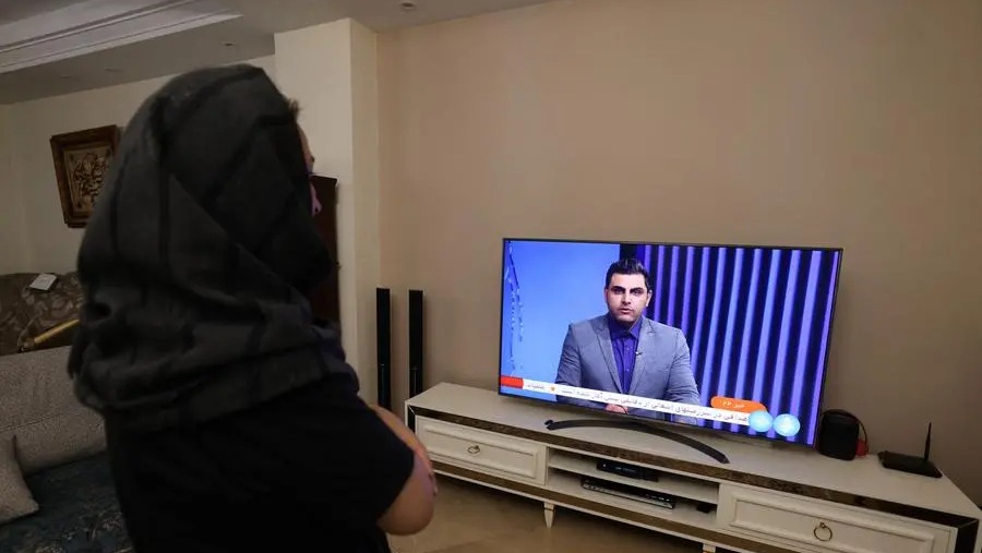 امرأة إيرانية تشاهد قناة تلفزيون إيرانية تغطي أخبار هجوم إيران على إسرائيل في 14 أبريل 2024