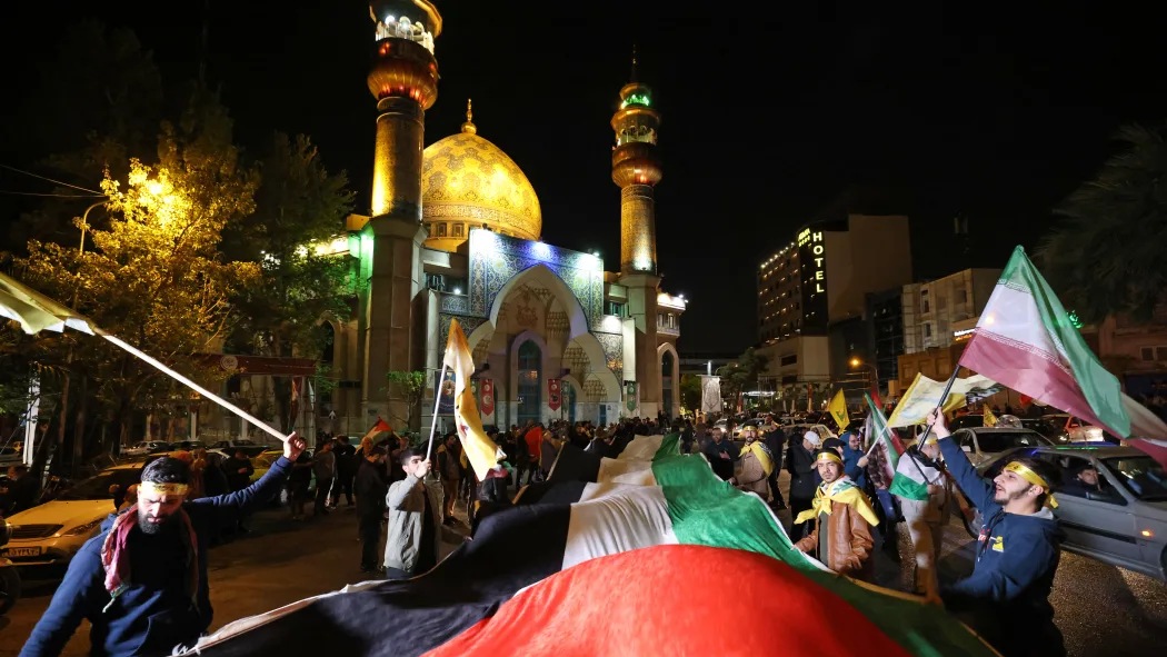  متظاهرون يرفعون أعلام إيران وفلسطين ويتجمعون في ساحة فلسطين في طهران بعد أن شنت إيران هجومًا بطائرات بدون طيار وصواريخ على إسرائيل