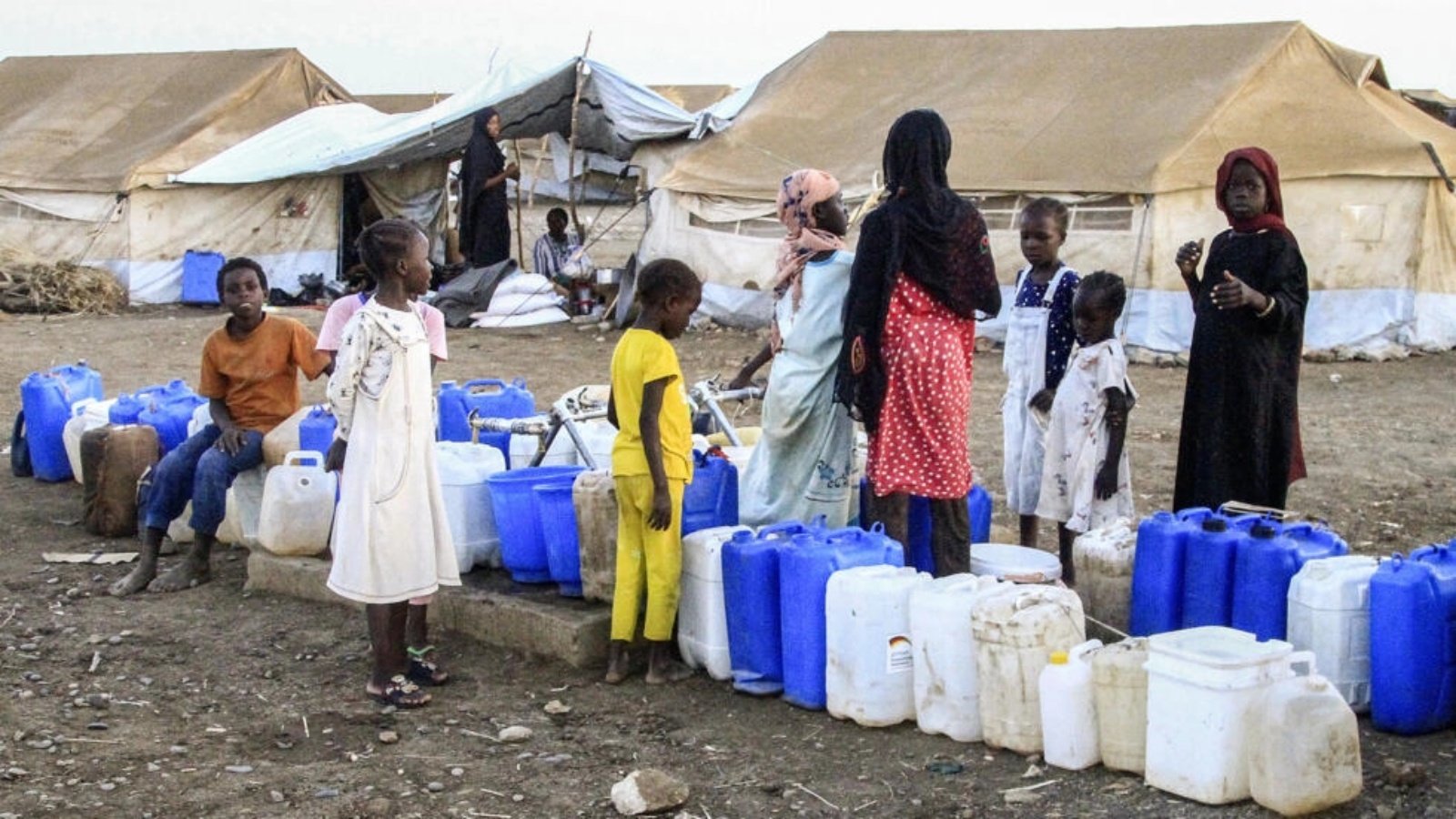 نساء وأطفال يحملون صفائح لتعبئة المياه في قضارف في شرق السودان في 29 آذار (مارس) 2024 
