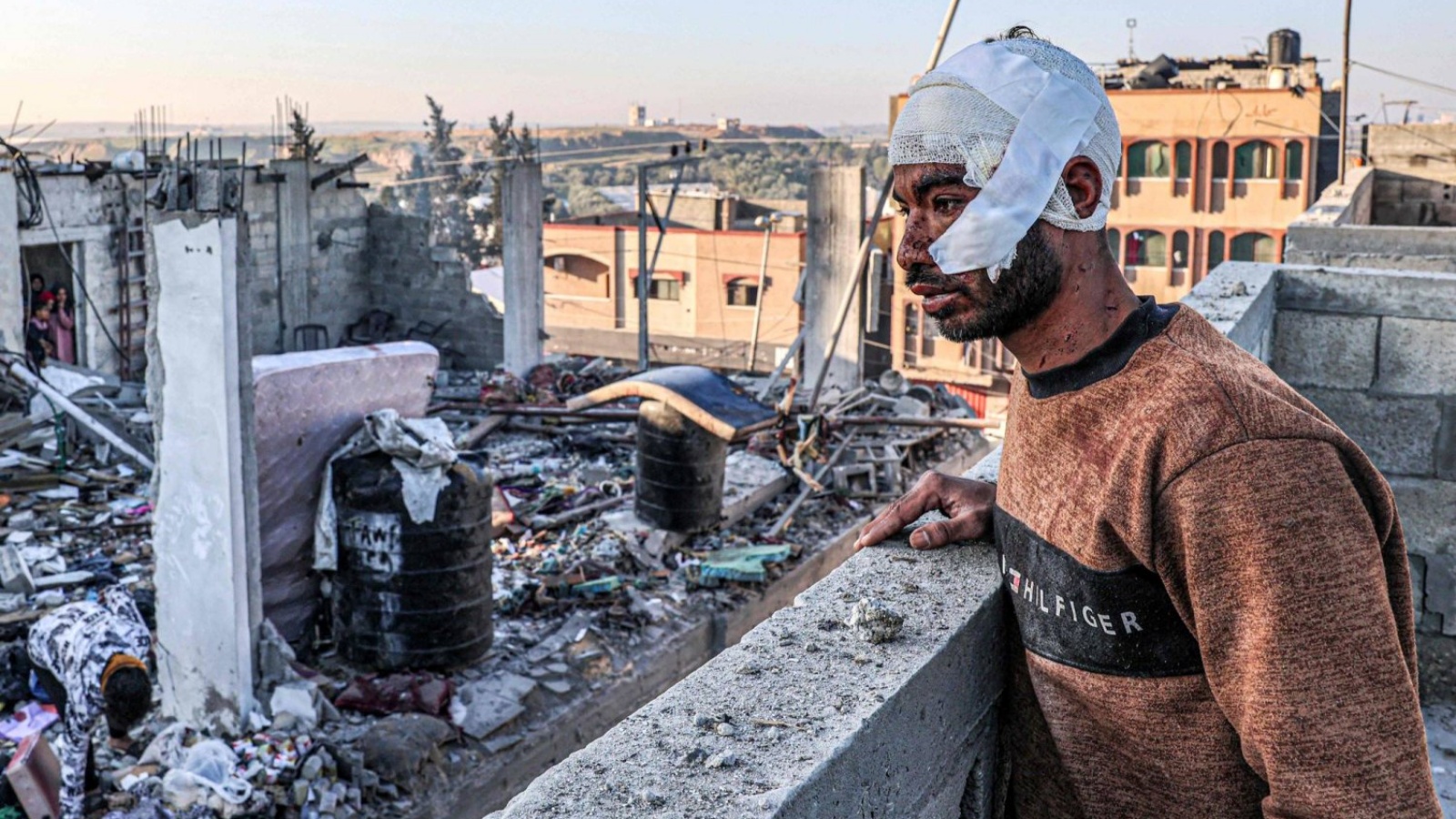 رجل جريح يقف أمام أنقاض مبانٍ مدمرة عقب القصف الإسرائيلي على رفح في جنوب قطاع غزة 