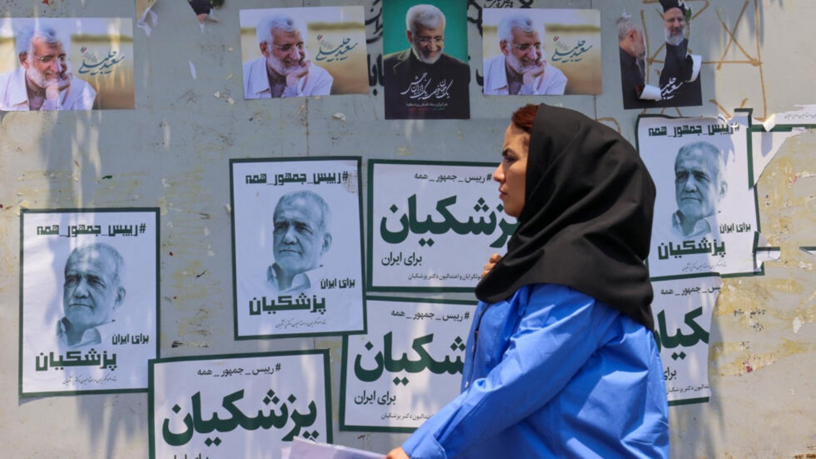 امرأة تمر أمام لافتات انتخابية لمرشحين في الانتخابات الرئاسية المبكرة في إيران، طهران في 20 حزيران (يونيو) 2024.