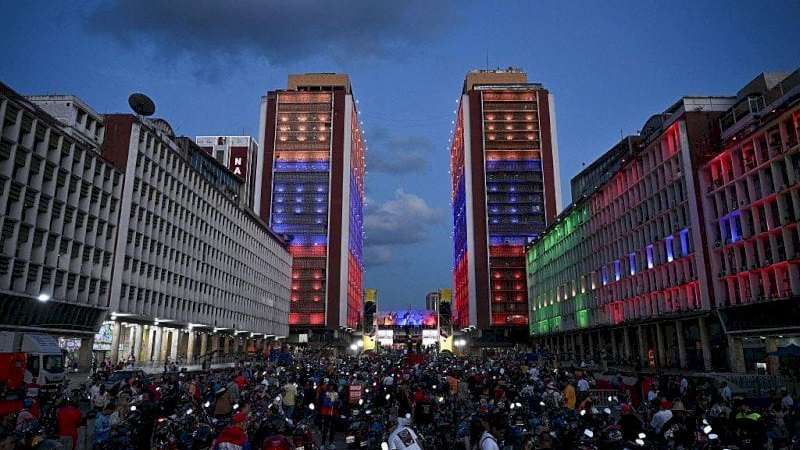 تظهر الصورة جموعاً غفيرة من المتظاهرين، بينما تضاء الأبنية المحيطة بهم بألوان العلم الفنزويلي. الصورة التقطت في المساء. - AFP via Getty Images