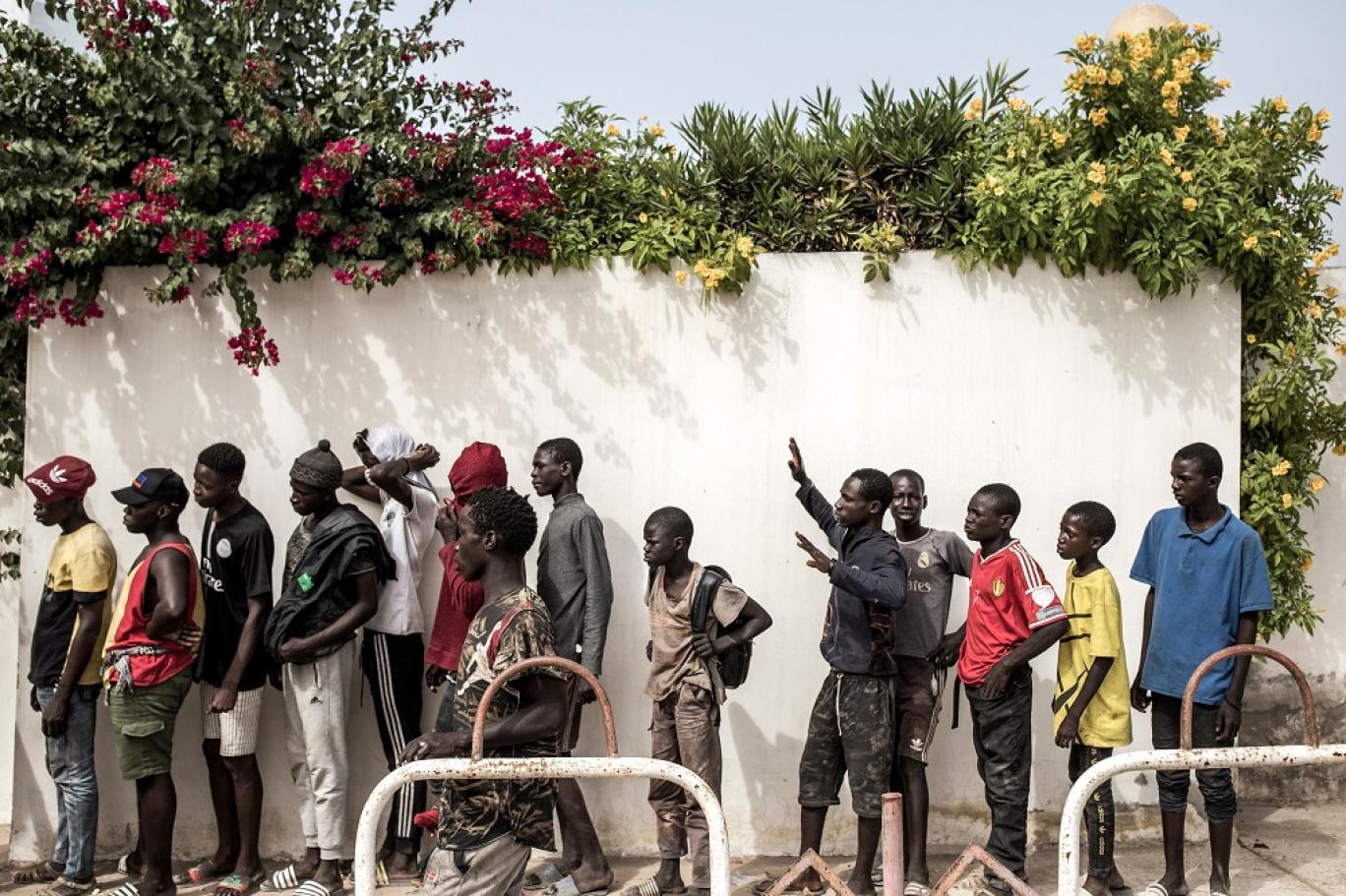 أطفال الشوارع يصطفون في عاصمة السنغال داكار لتلقي الطعام بعد تفشي كورونا (أ.ف.ب)