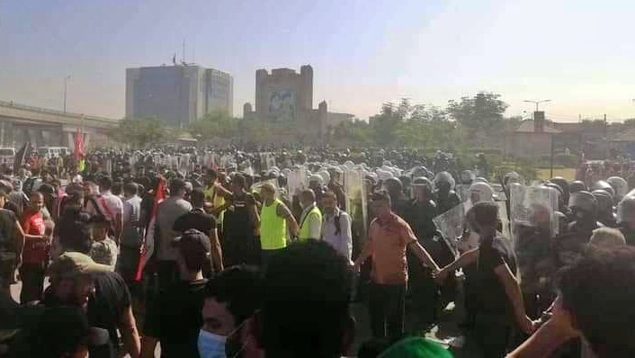 المتظاهرون في بغداد يشكلون سلسلة بشرية بينهم وبين قوات مكافحة الشغب