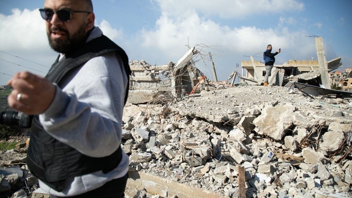لبنانيان على انقاض منازل دمرها القصف الإسرائيلي في بلدة حولا الجنوبية