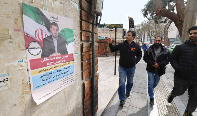مارة بالقرب من ملصق انتخابي في طهران التي تستعد لانتخابات قريباً