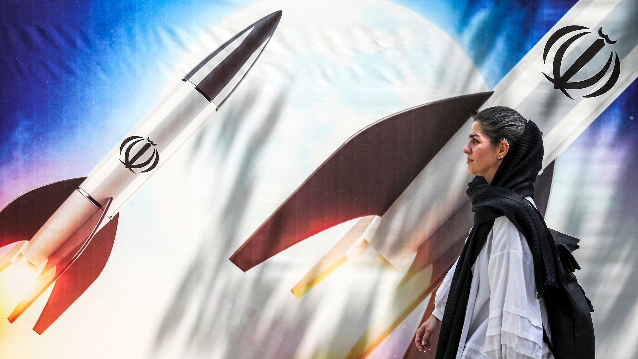 امرأة تسير بالقرب من جدارية في طهران تستعرض قدرات إيران الصاروخية
