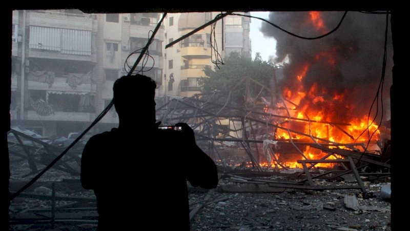 لبناني يلتقط صورةً لموقع مبنى استهدفته إسرائيل في الضاحية الجنوبية لبيروت