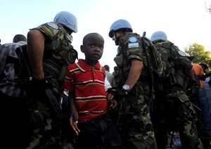 فتى يقف امام قوات حفظ السلام خلال توزيع المساعدات الغذائية