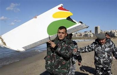 شرطي لبناني يحمل جزء من جناح الطائرة بعد العثور عليه يوم 26 يناير 2010