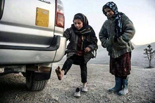 فتاة سورية تحاول تدفئة قدمها خلف عادم سيارة
