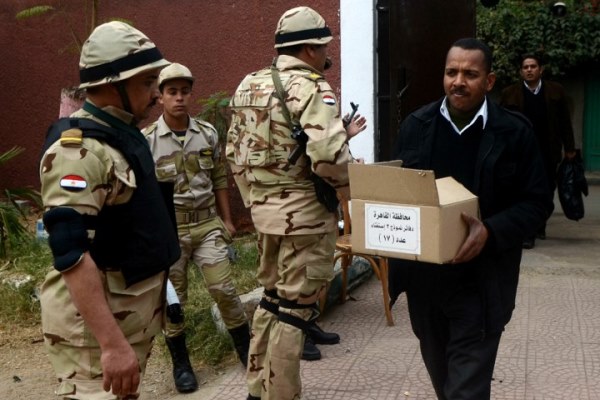 رجل يحمل صندوق اقتراع يمر أمام مجموعة من الجنود المصريين