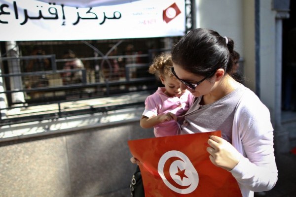 تونسية تحمل علم بلدها أمام أحد مراكز الاقتراع