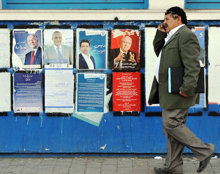 تونسي يمر أمام معلقات دعائية لمرشحين للرئاسة وعددهم 27 مرشحا
