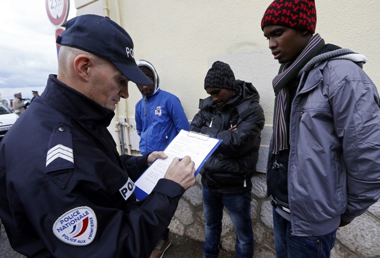 شرطي فرنسي بصدد إيقاف مهاجرين أفارقة غير شرعيين بالقرب من محطة قطارات