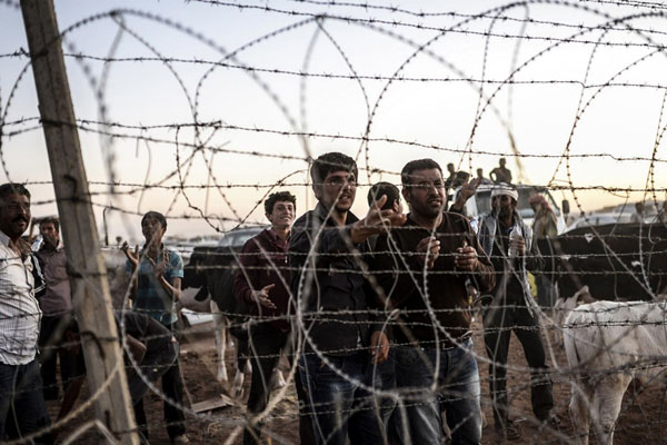 سوريون أمام شريط شائك على الحدود مع تركيا