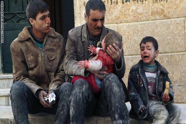 حلبي يحمل طفلاً نجا من غارة جوية شنتها طائرات بشار الأسد