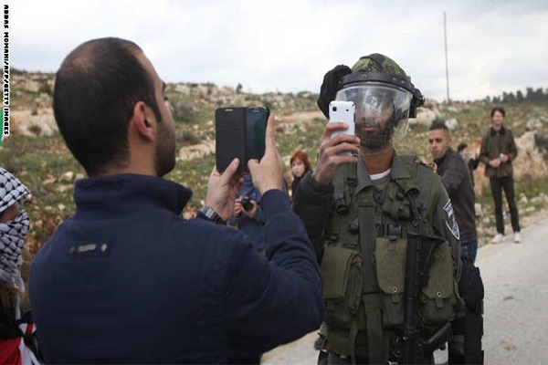 فلسطيني وجندي إسرائيلي يتبادلان التقاط الصور بعد تظاهرة في الضفة الغربية