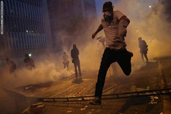 متظاهرون يهربون من غاز مسيل للدموع أطلقه الحرس الوطني الفنزويلي