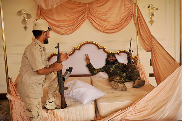 ثوار ليبيون على سرير زعيمهم المقتول معمر القذافي