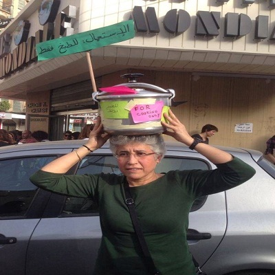 سيدة تحمل وعاء طبخ على رأسها كنوع من الاحتجاج على الاعتداءات على المرأة
