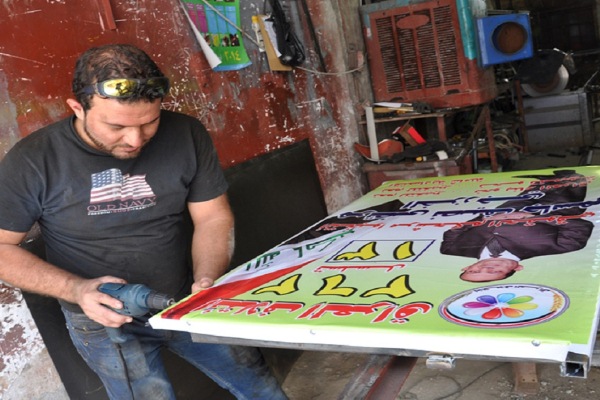 عامل عراقي يعمل على ملصقات انتخابية