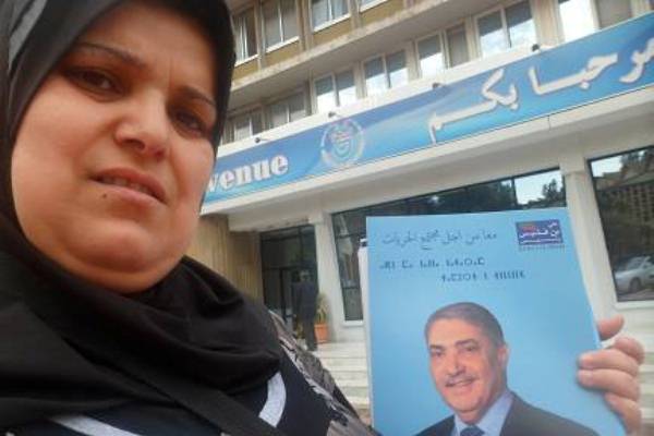 جزائرية تحمل ملصقاً انتخابياً للمرشح بن فليس