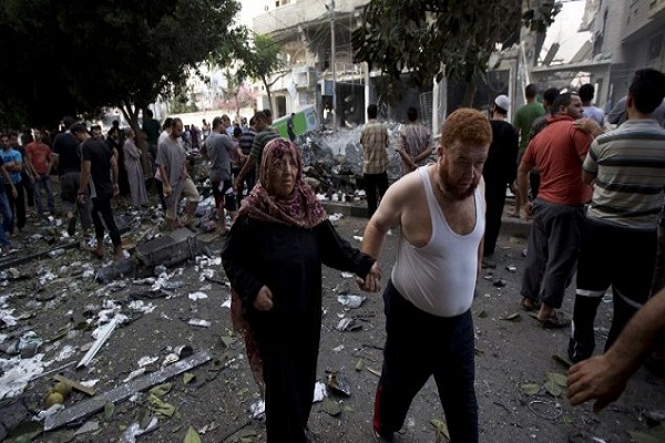 مواطن في غزة يمسك بيد زوجته بعد قصف منزلهما