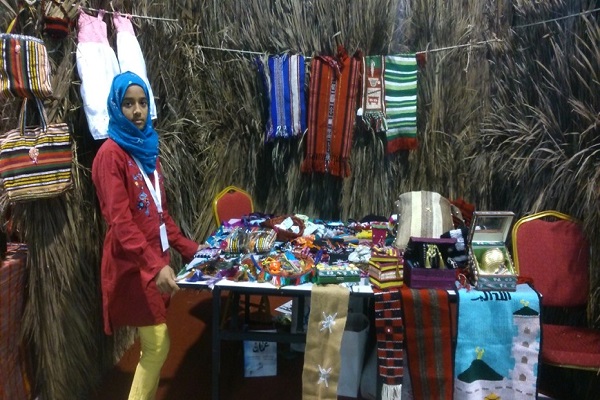 فتاة عمانية تعرض بعض المشغولات النسيجية