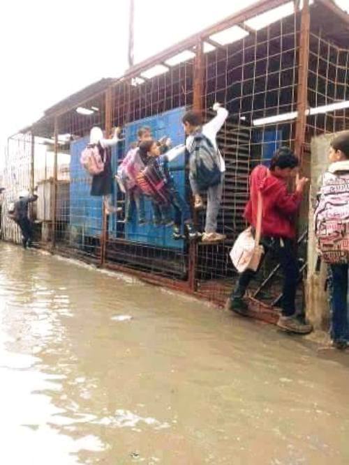تلاميذ عراقيون يحاولون تخطي فيضان الامطار والوصول الى مدرستهم