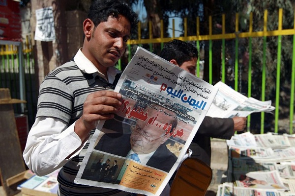 يمني يقرأ صحيفة تتصدر صفحتها الأولى صورة للرئيس عبد ربه منصور هادي