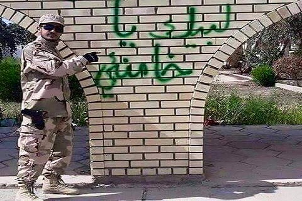 أحد عناصر المليشيات العراقية يكتب عبارات مؤيدة لخامنئي على احد الجدران بتكريت