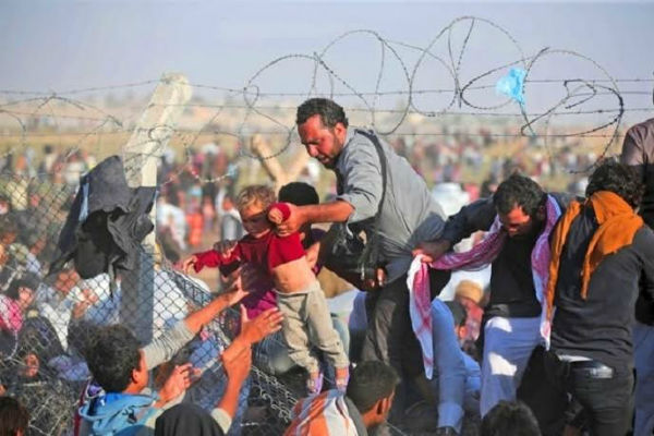 مواطن سوري يحاول نقل ابنه الصغير عبر الأسلاك الحدودية