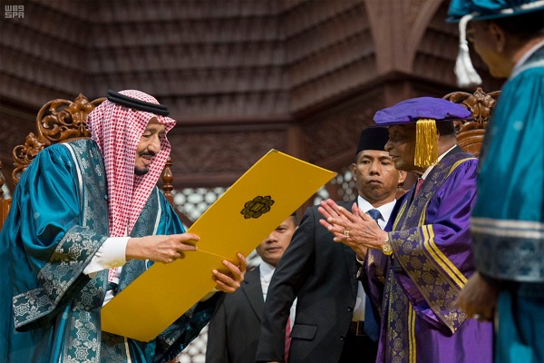 الملك سلمان خلال تسلمه الدكتوراة الفخرية من رئيس الجامعة
