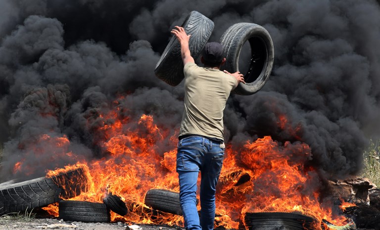 شاب فلسطيني يحرق الاطارات بالقرب من الحدود بين غزة واسرائيل