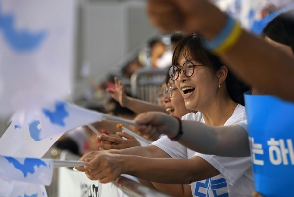 كوريون جنوبيون يلوحون بالعلم الموحد خلال متابعتهم منافسات في كرة الطاولة في مدينة دايجون الكورية الجنوبية