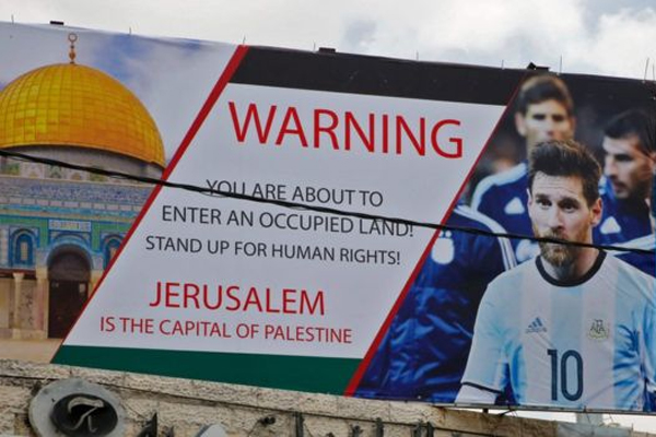 صورة ميسي على لافتة في الضفة الغربية تدعو لإلغاء المباراة