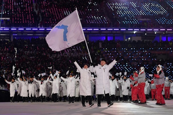 لاعبين من الكوريتين يسيرون معا خلال دورة الألعاب الأولمبية الشتوية هذا العام في بيونغ تشانغ بتاريخ 9 شباط/فبراير 2018