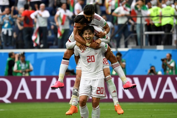 لاعب المنتخب الايراني لكرة القدم سردار آزمون يحمل على كتفيه اثنين من زملائه، احتفالا بالفوز على المغرب