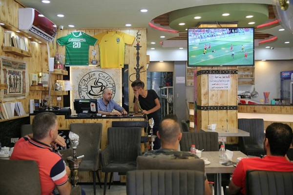 مشجعون يتابعون في أحد مقاهي بغداد، مباراة في كأس العالم لكرة القدم المقامة في روسيا، في 23 حزيران/يونيو 2018.