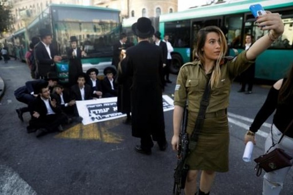 جندية اسرائيلية تلتقط صورة لنفسها باستخدام هاتفها النقال مع متظاهرين يهود من الارثوذكس المتشددين في القدس