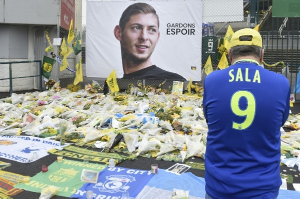 مشجع يرتدي قميص سالا أمام صورة له وباقات من الزهر خارج ملعب فريق نانت الفرنسي