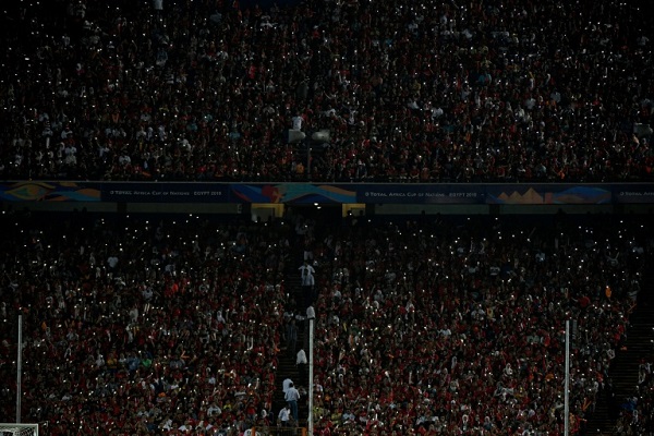 مشجعون مصريون يضيئون هواتفهم النقالة في مدرجات ستاد القاهرة الدولي خلال مباراة مصر وجنوب إفريقيا