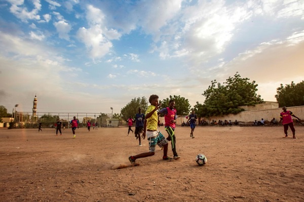 شباب سودانيون يلعبون مباراة لكرة القدم في ساحة ترابية غير مجهزة في الخرطوم