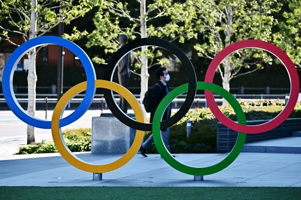شخص يرتدي الكمامة يمر خلف مجسم الحلقات الاولمبية في طوكيو في 28 شباط/فبراير 2020.